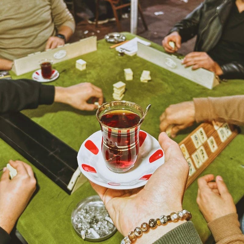Several hands reaching over a shared game board on a wooden table - a stand-in for the Pandemic, not a photograph of this model
