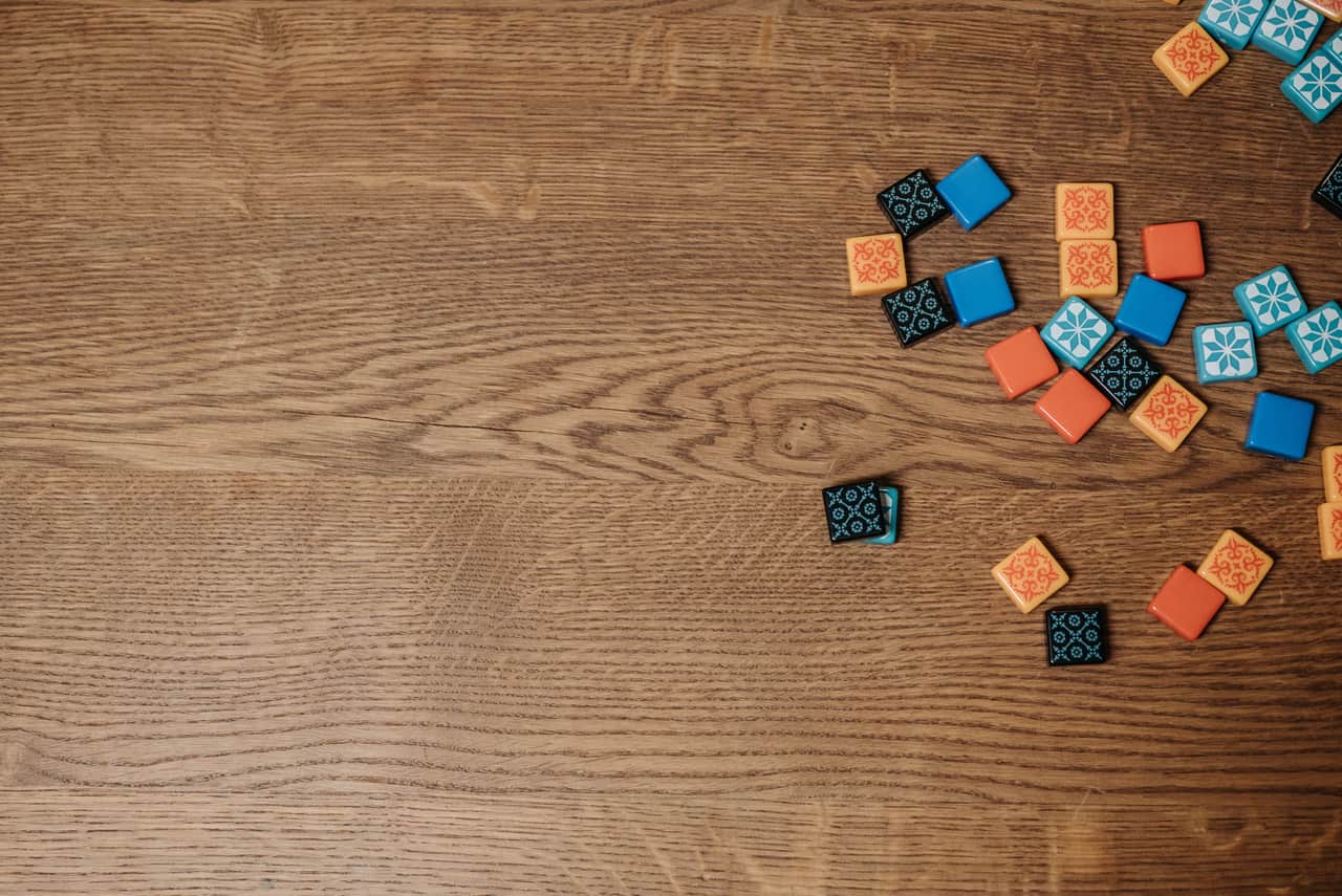A board game part-way through play on a wooden table, with wooden pieces and cards spread out