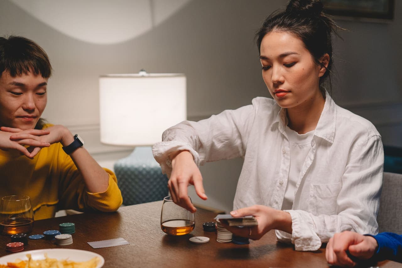 Two adults playing a card game at a wooden table in the evening