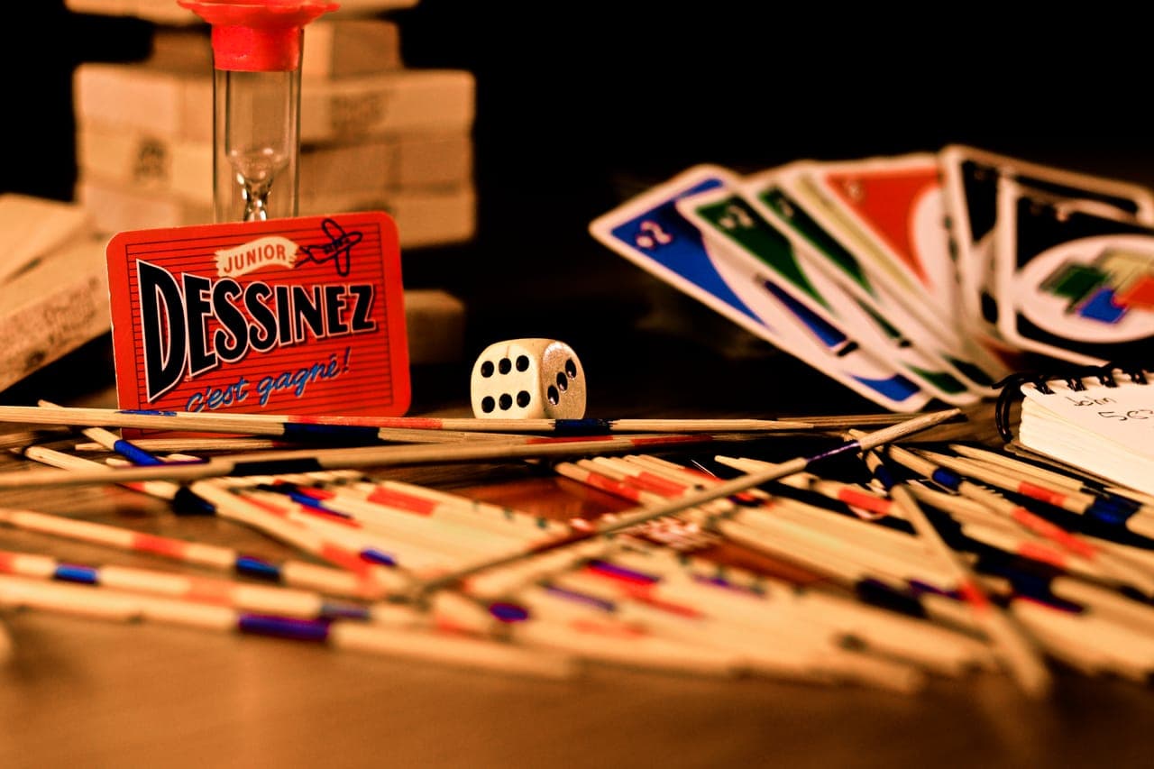 Playing cards, dice and game pieces spread together across a table