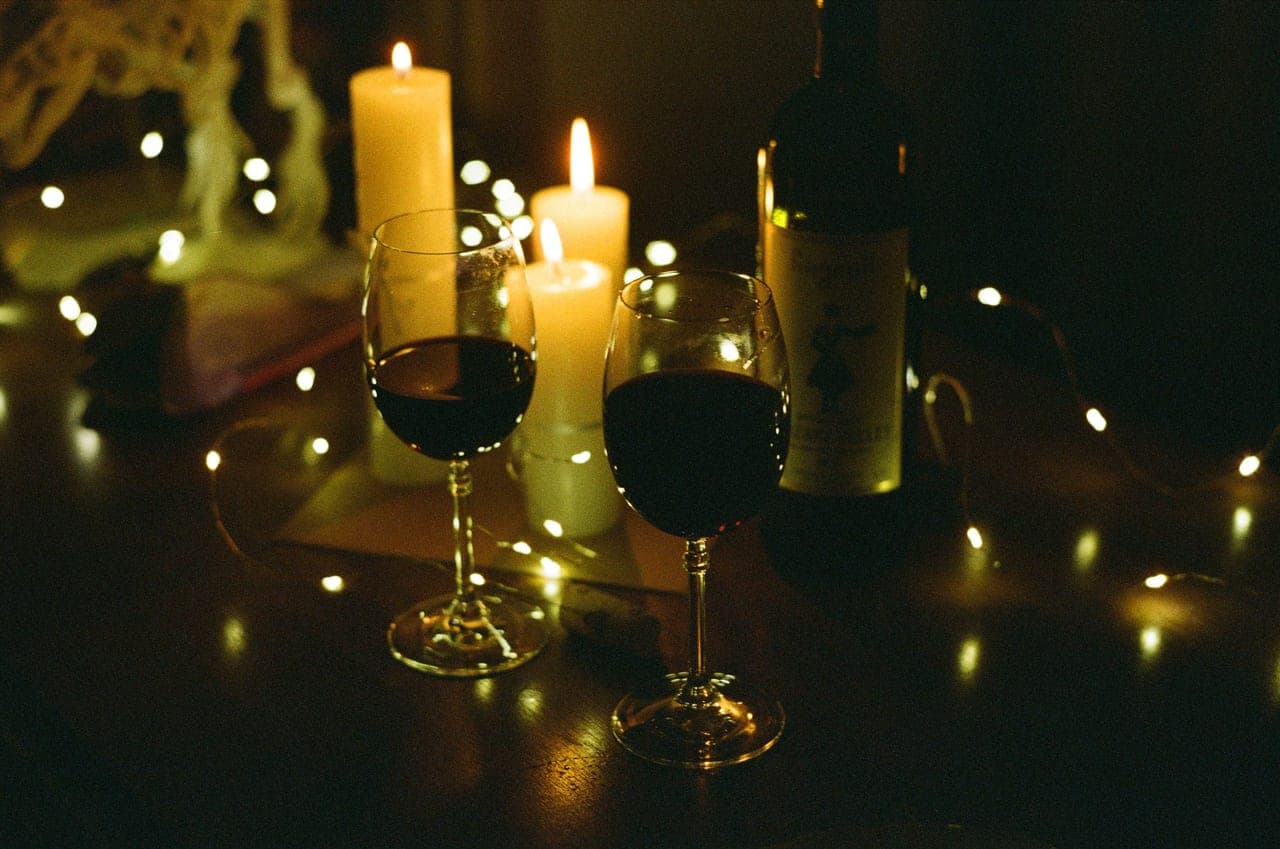 Two glasses of wine beside a small game laid out on a table at night