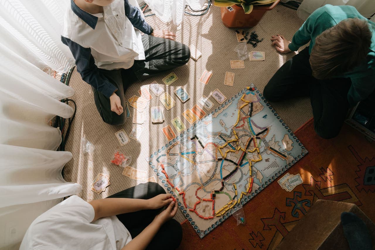 School-age children playing a map-based board game together on a rug