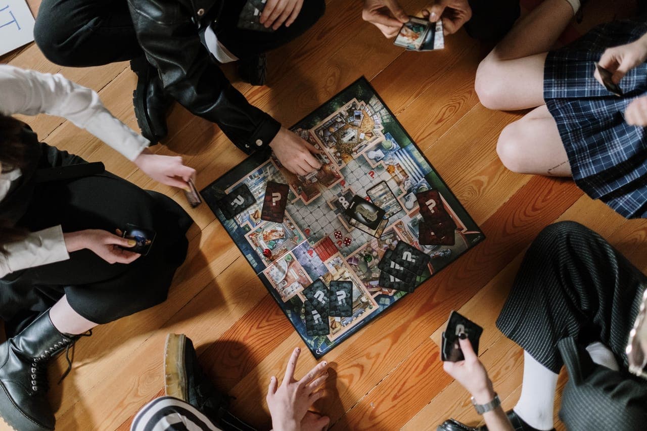 Overhead view of a group of friends playing a board game together on the floor