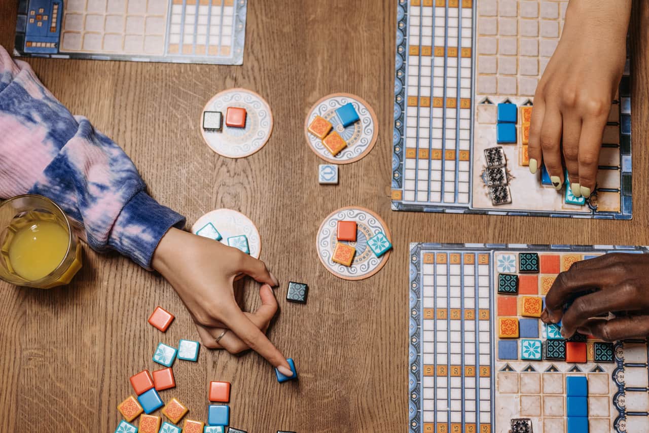Four people playing a board game around a wooden dining table