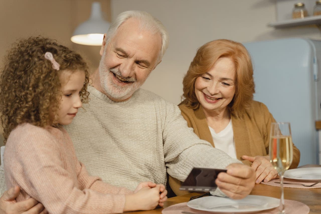 An older couple playing a board game with a grandchild at a kitchen table