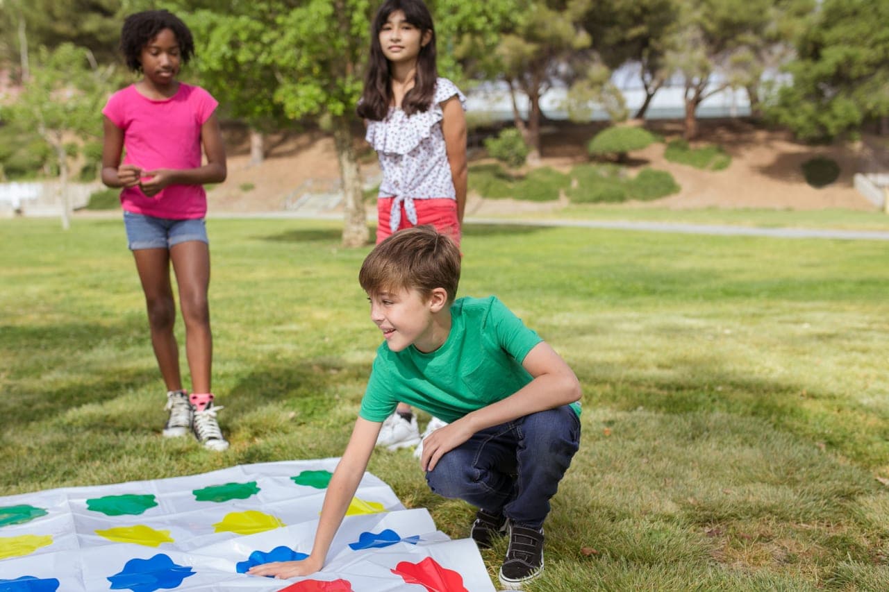 Young children placing colorful tiles on a board game at a low table