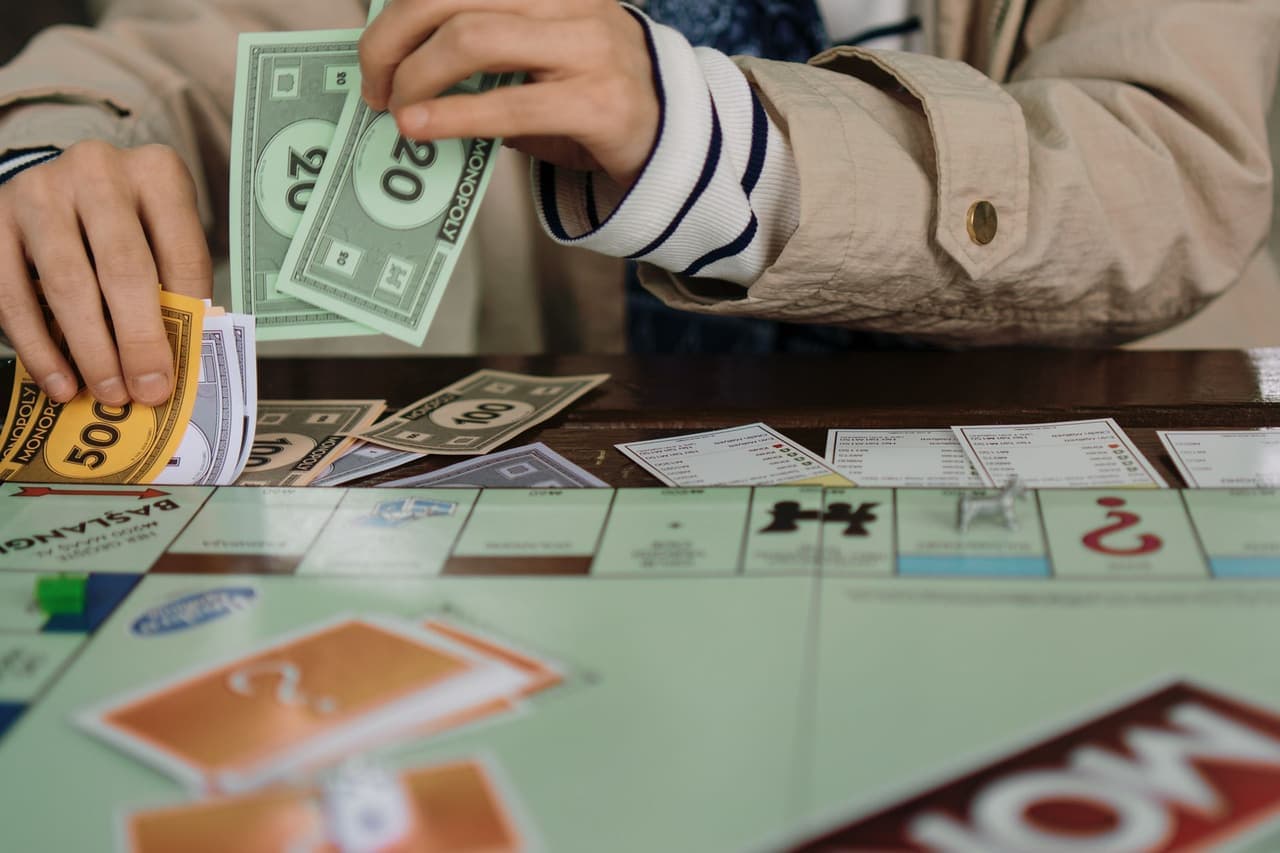 Hands counting play money over a Monopoly board