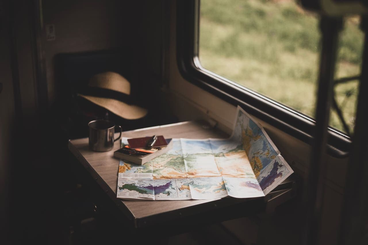 A folded paper map open on a small table beside a train window