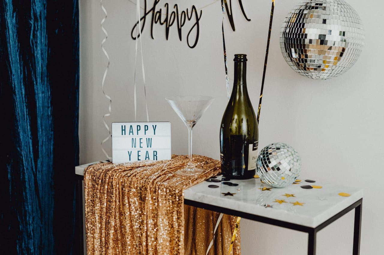 A New Year's Eve table with champagne, a disco ball and gold decorations