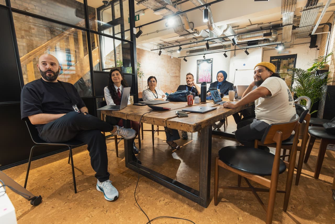 Colleagues gathered around a meeting-room table playing a card game