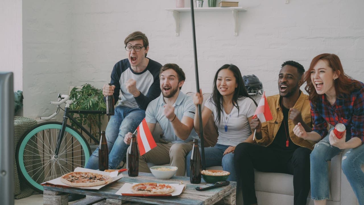A group of adults laughing together during a party game in a living room