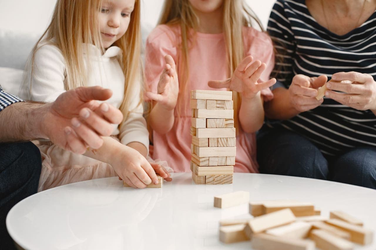 A family taking turns at a wooden block-stacking game around a low table