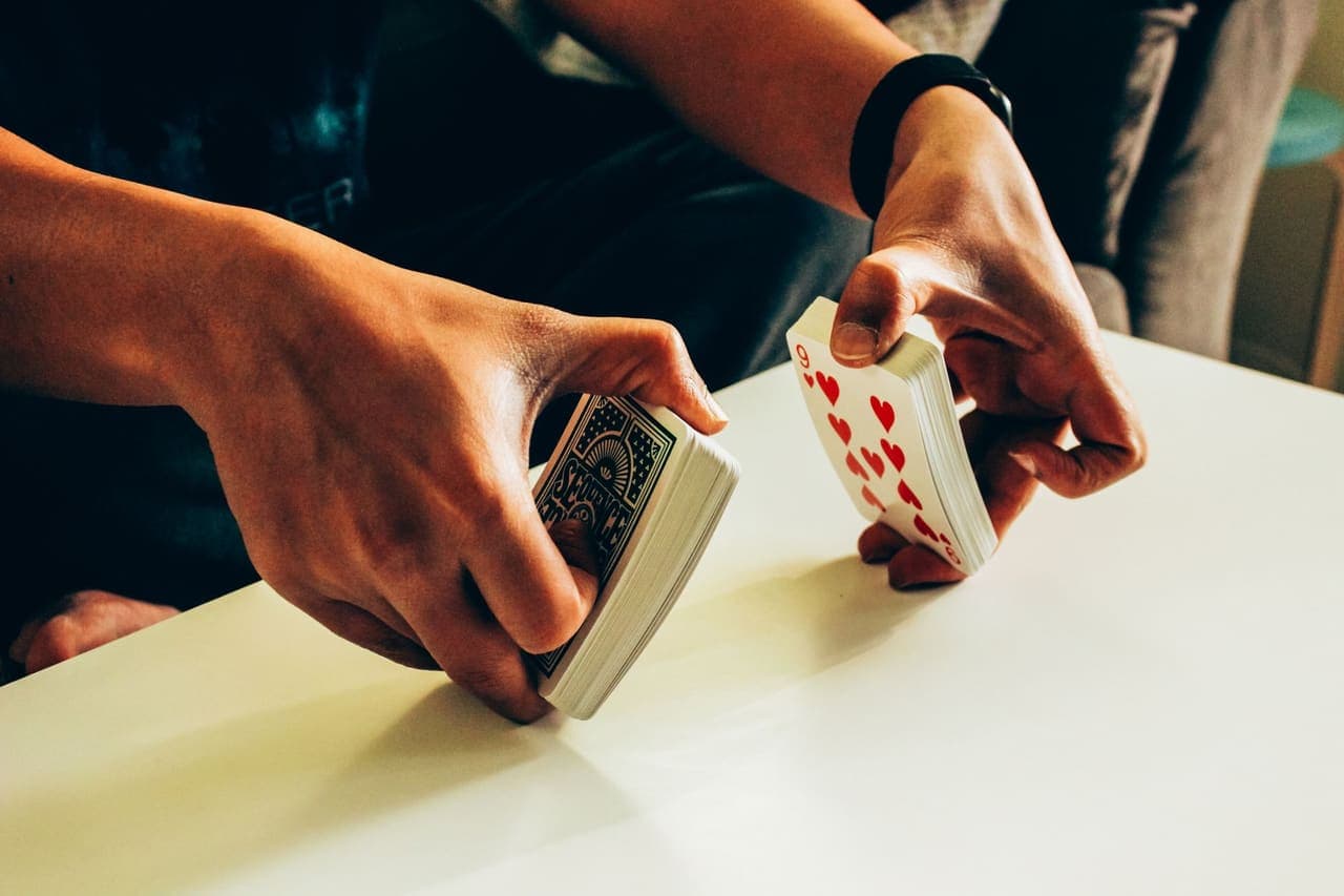A pair of hands shuffling a deck of cards on a table