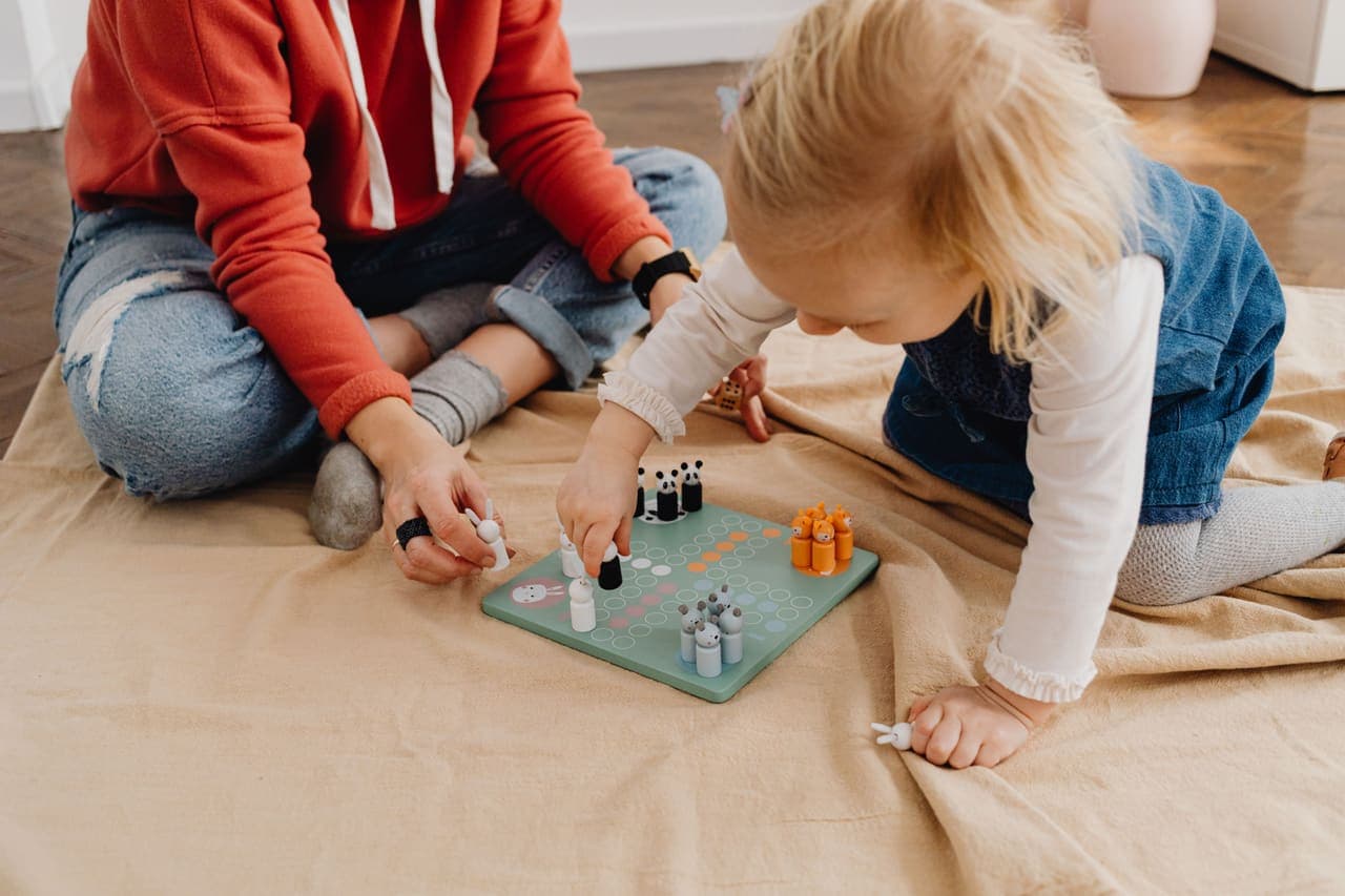 Two young children kneeling on the floor over a colorful board game