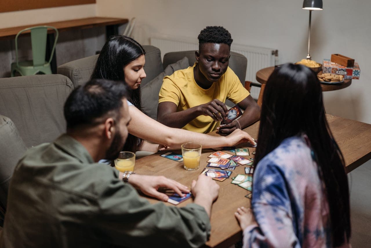 A group of teenagers gathered around a table playing a card game