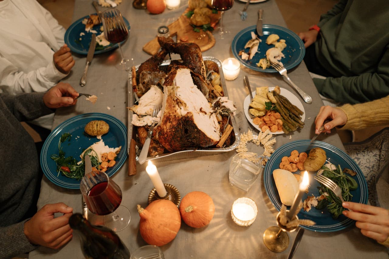 A long family table after a holiday meal, plates pushed back and a game brought out
