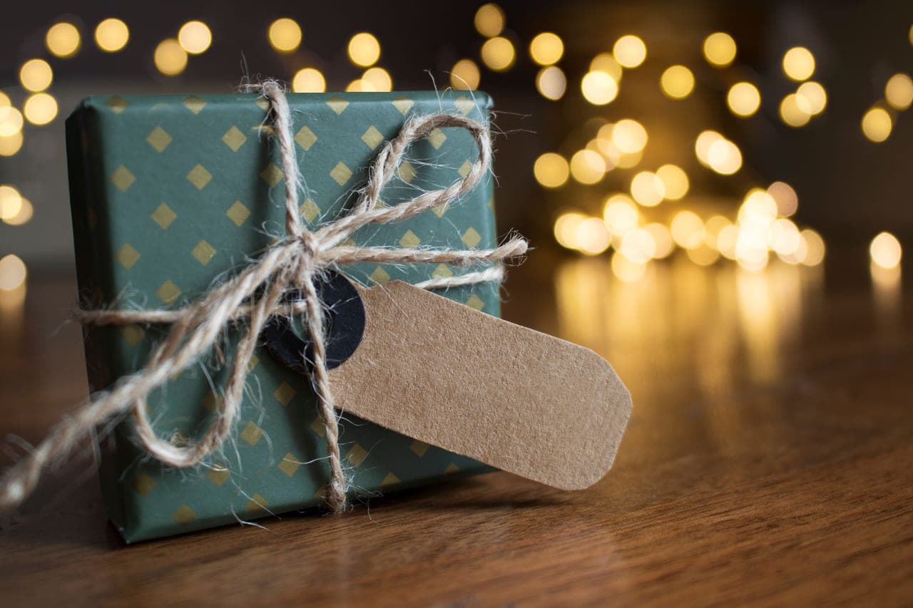 A wrapped gift box and a board game beside a table set for a gathering